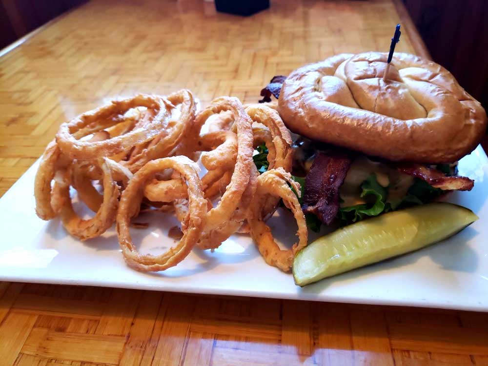Enjoy a burger with onion rings topped with bacon by Cheers Grille & Bar in Concord NH.