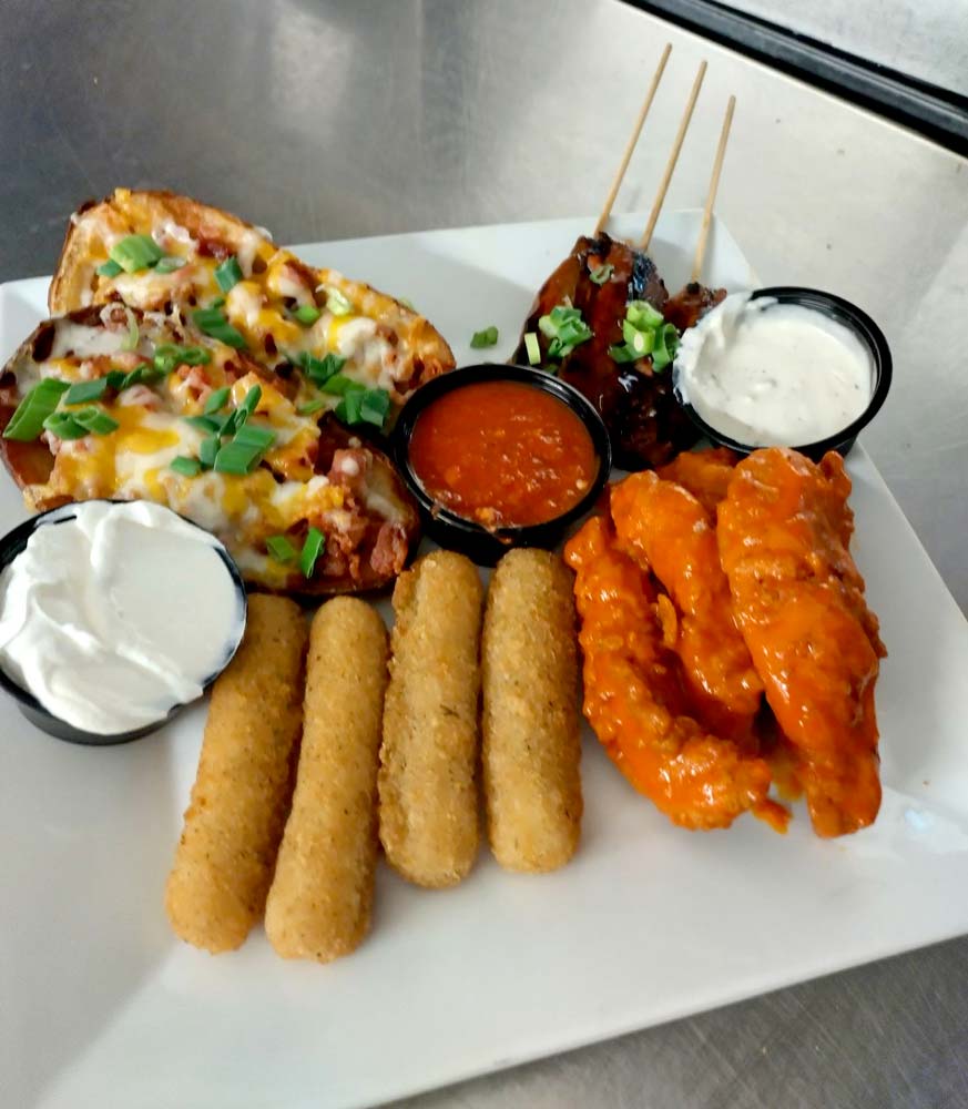 Appetizer combo platter with chicken lips, mozzarella sticks, beef tips, and potato skins. Served with sour cream and dressing at Cheers Grille & Bar in Concord NH.